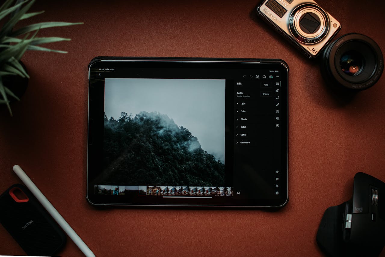 A digital photo editing setup featuring a tablet, camera, and accessories on a desk.