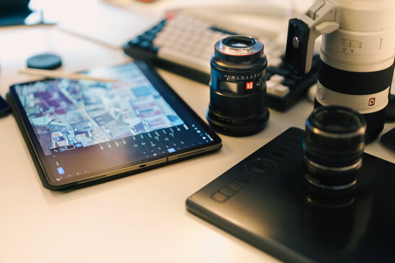 A modern photographer's workspace featuring lenses, tablet, and digital editing setup.